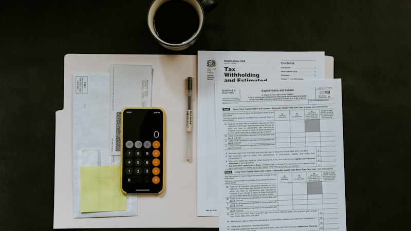 Financial invoicing documents, tax calculation worksheets, and pen on professional office desk